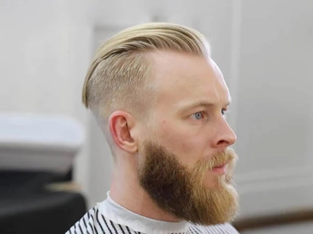 Profil mężczyzny ze slick back i wysokim fade, z widoczną linią włosów.
